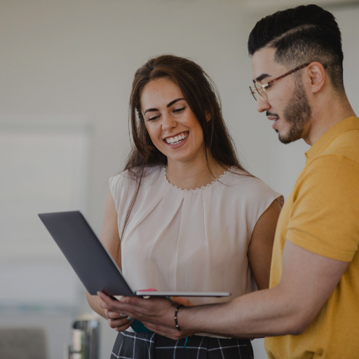 Two adults looking at a laptop smiling 